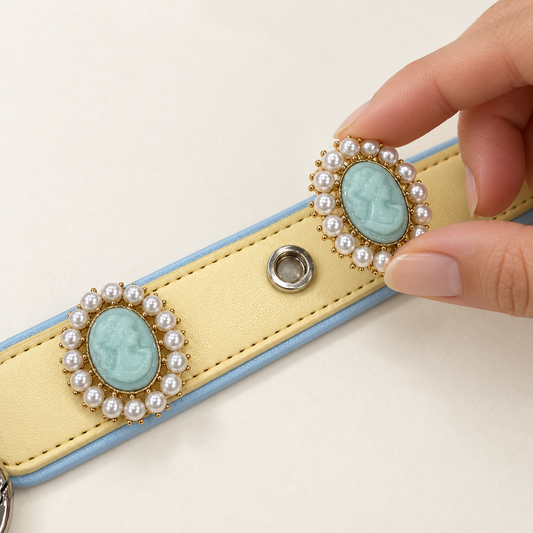 Hand attaching a blue pearl cameo dog collar charm to a yellow PETIRIA collar