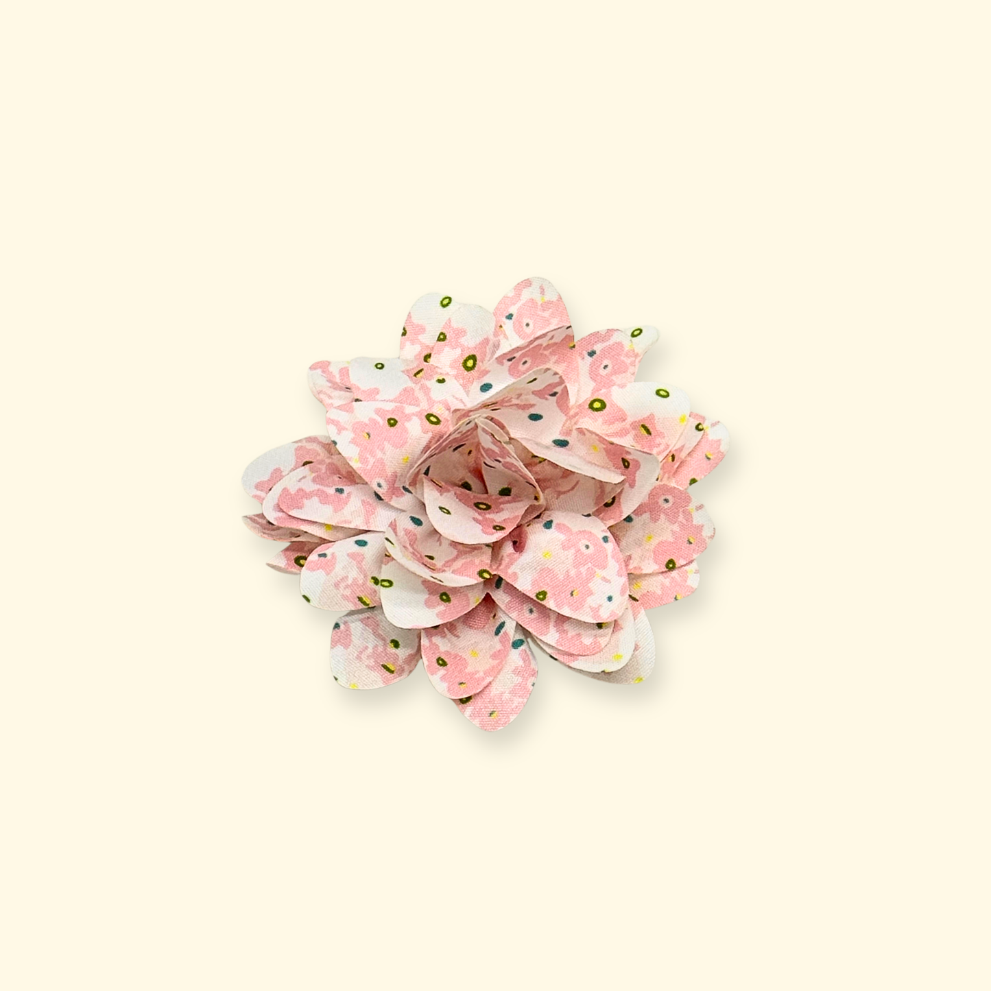 Close-up of Petiria pink floral collar charm on beige background, showing layered petals and delicate design