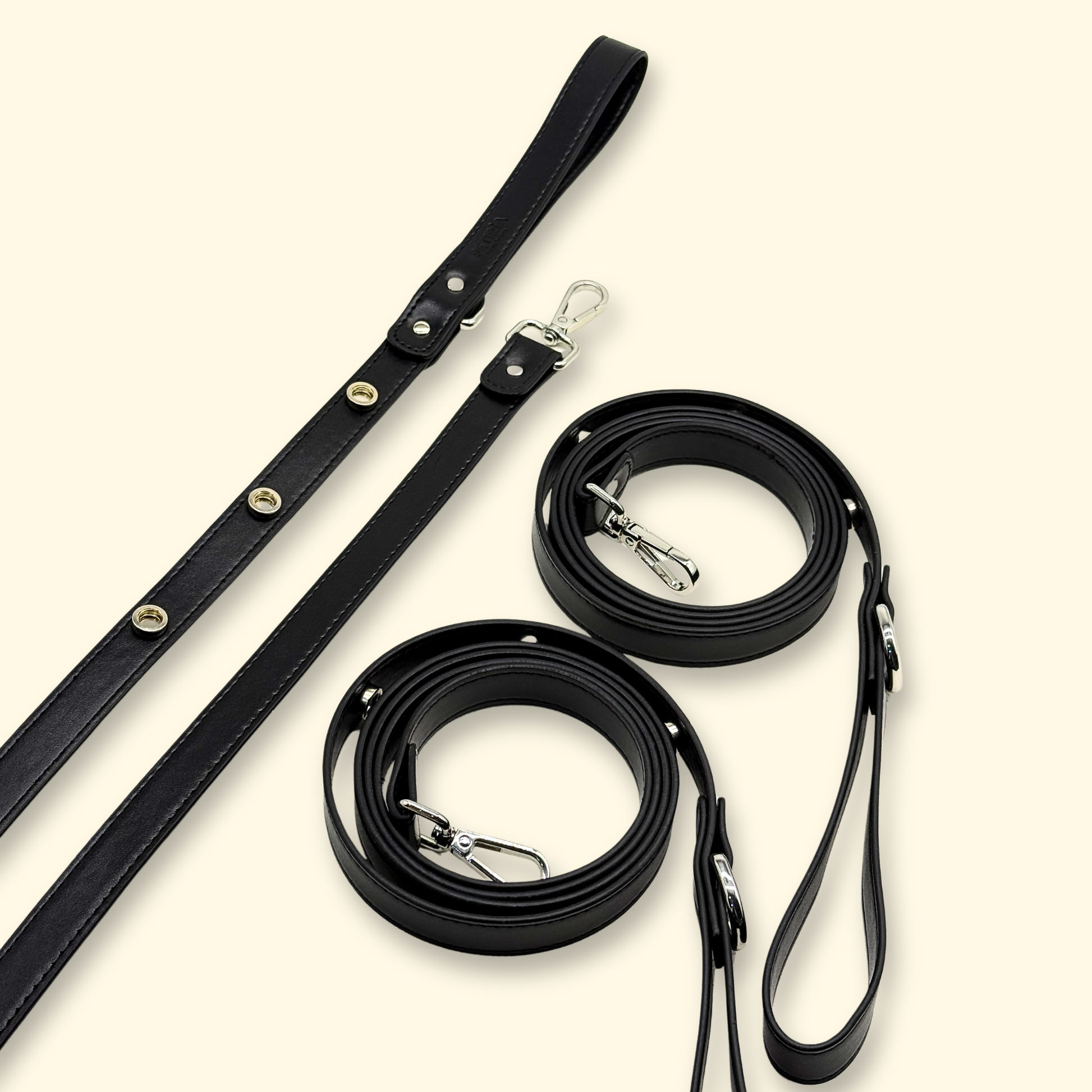 Three black interchangeable dog leashes with charm snaps displayed together on a light cream background