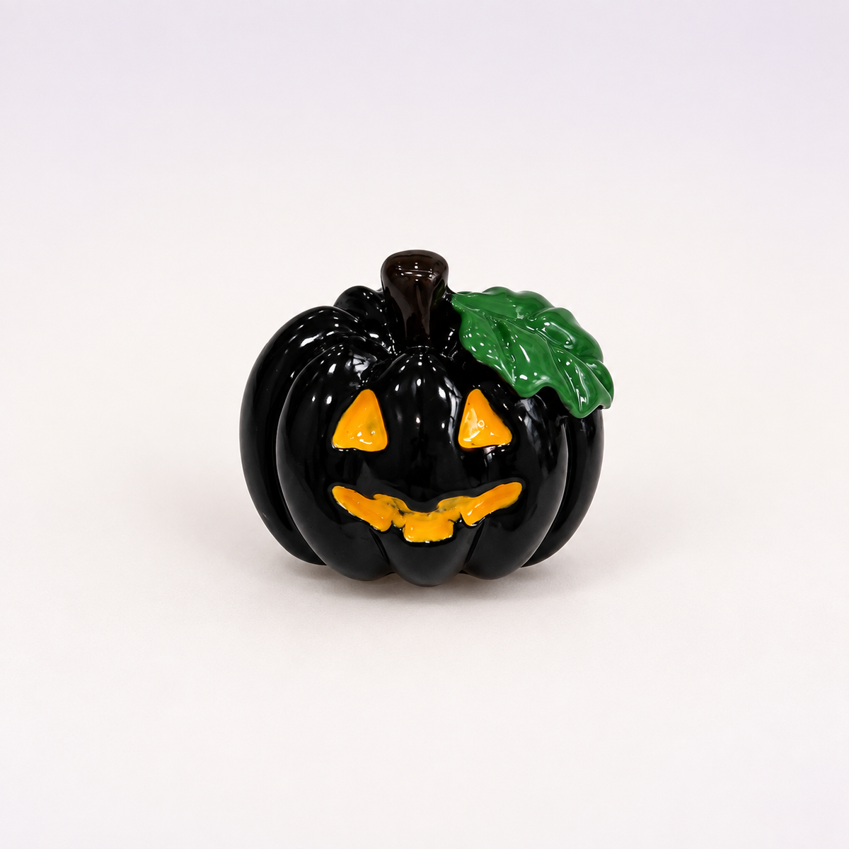 Black jack-o-lantern dog collar charm with orange face and green leaf detail for Halloween