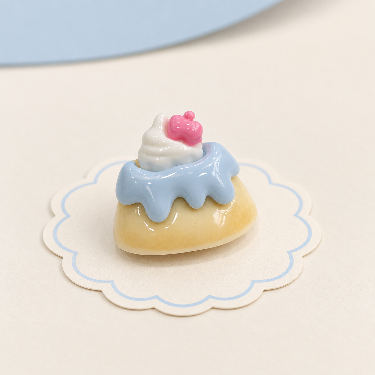 Blue frosting cake dog collar charm with cream topping and a small pink dessert detail