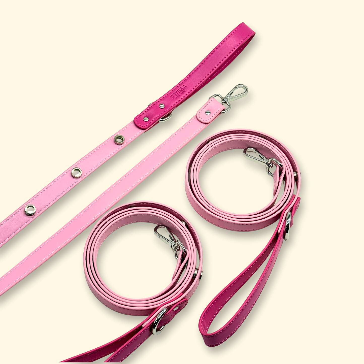 Two blush pink dog leashes laid flat, showing the full length and silver metal handles, on a light beige background.