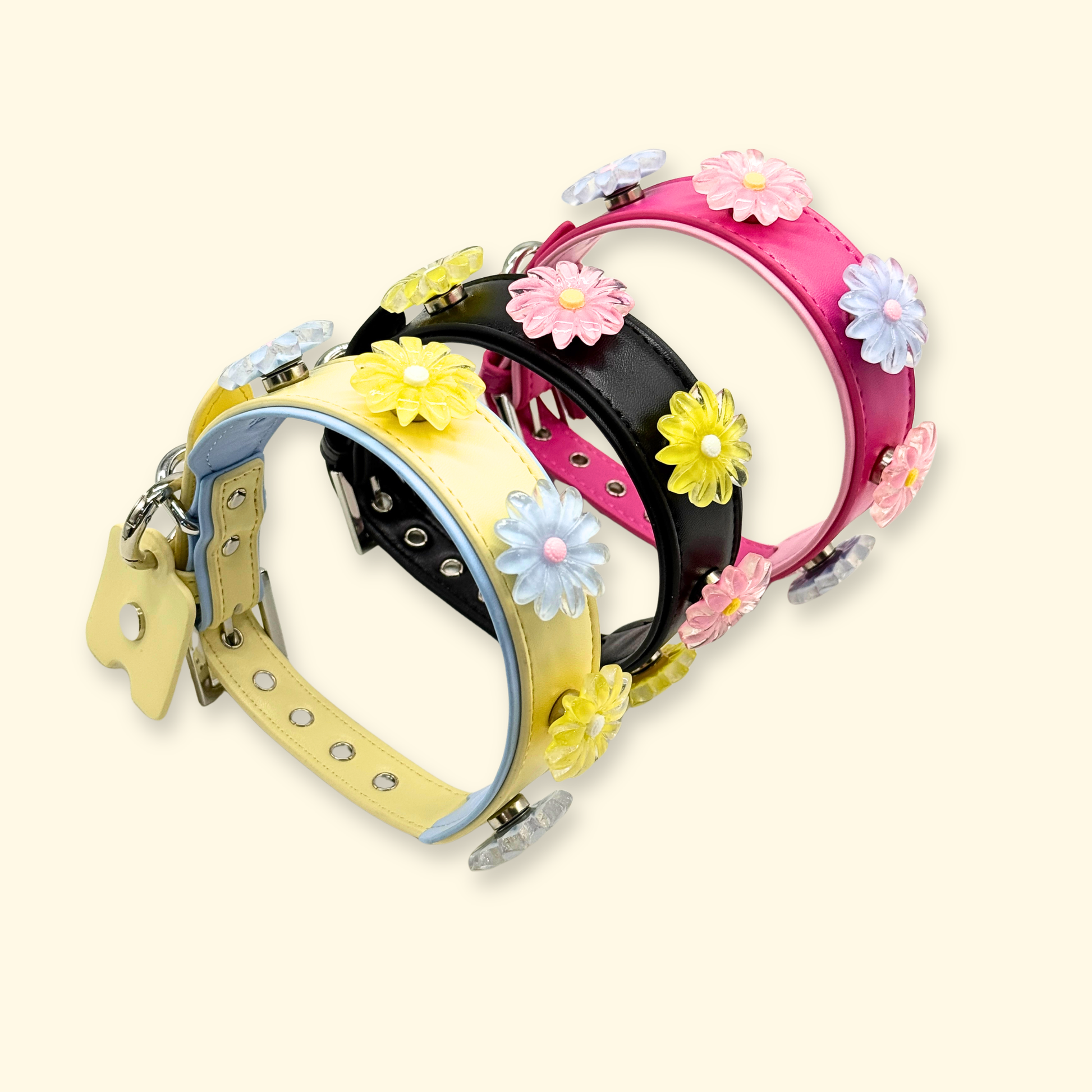 Multiple dog collars styled with colorful snap-on daisy flower charms in pink, yellow, and blue for interchangeable pet fashion