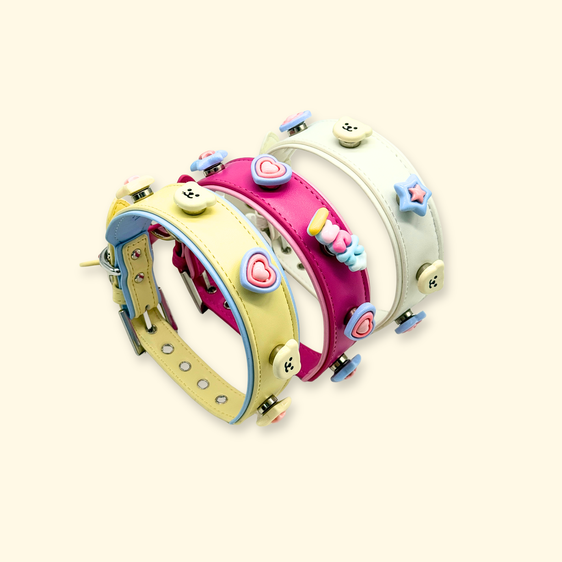 Three pastel dog collars arranged in a curved display with multiple snap-on charms showcasing a customizable pet collar system
