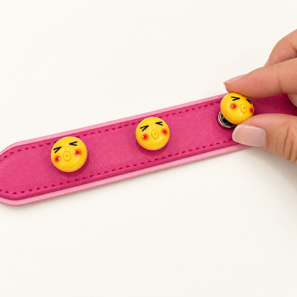 Yellow emoji dog collar charm being snapped onto a pink Petiria interchangeable charm collar