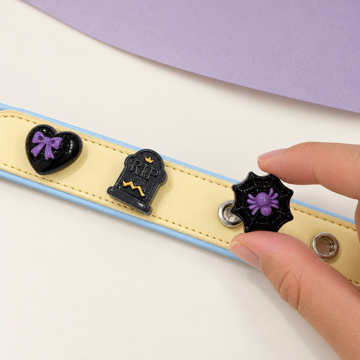 Purple spider web dog collar charm being snapped onto a Petiria interchangeable charm collar for Halloween