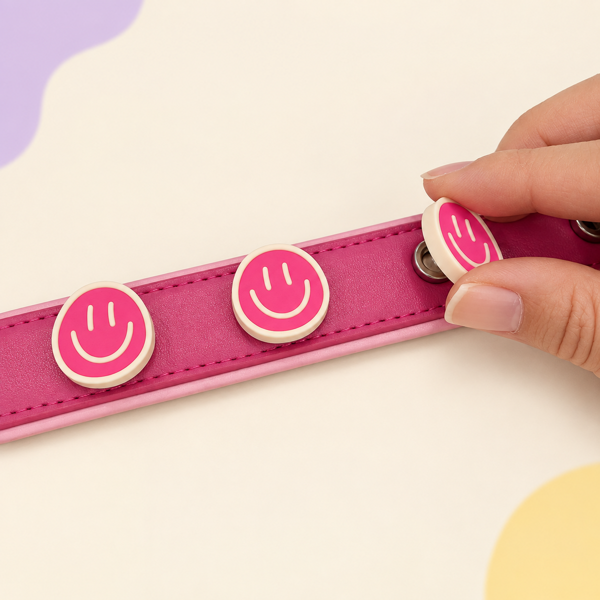 Pink smiley face dog collar charm being snapped onto a pink Petiria interchangeable charm collar