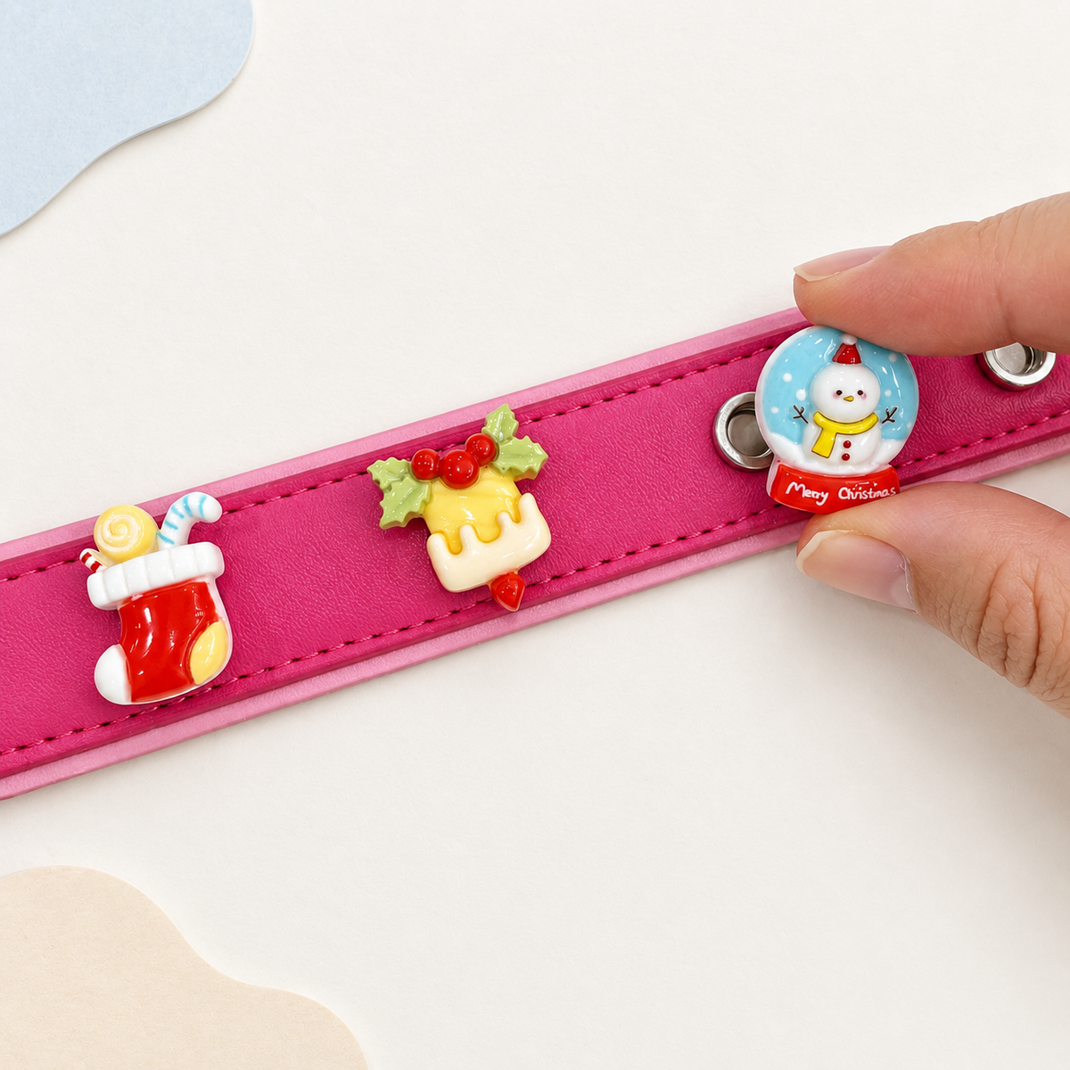Snowman and winter Christmas dog collar charms being snapped onto a pink Petiria interchangeable charm collar