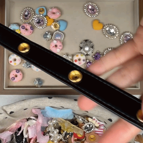 Hands attaching interchangeable charms onto a black dog leash with snap button design