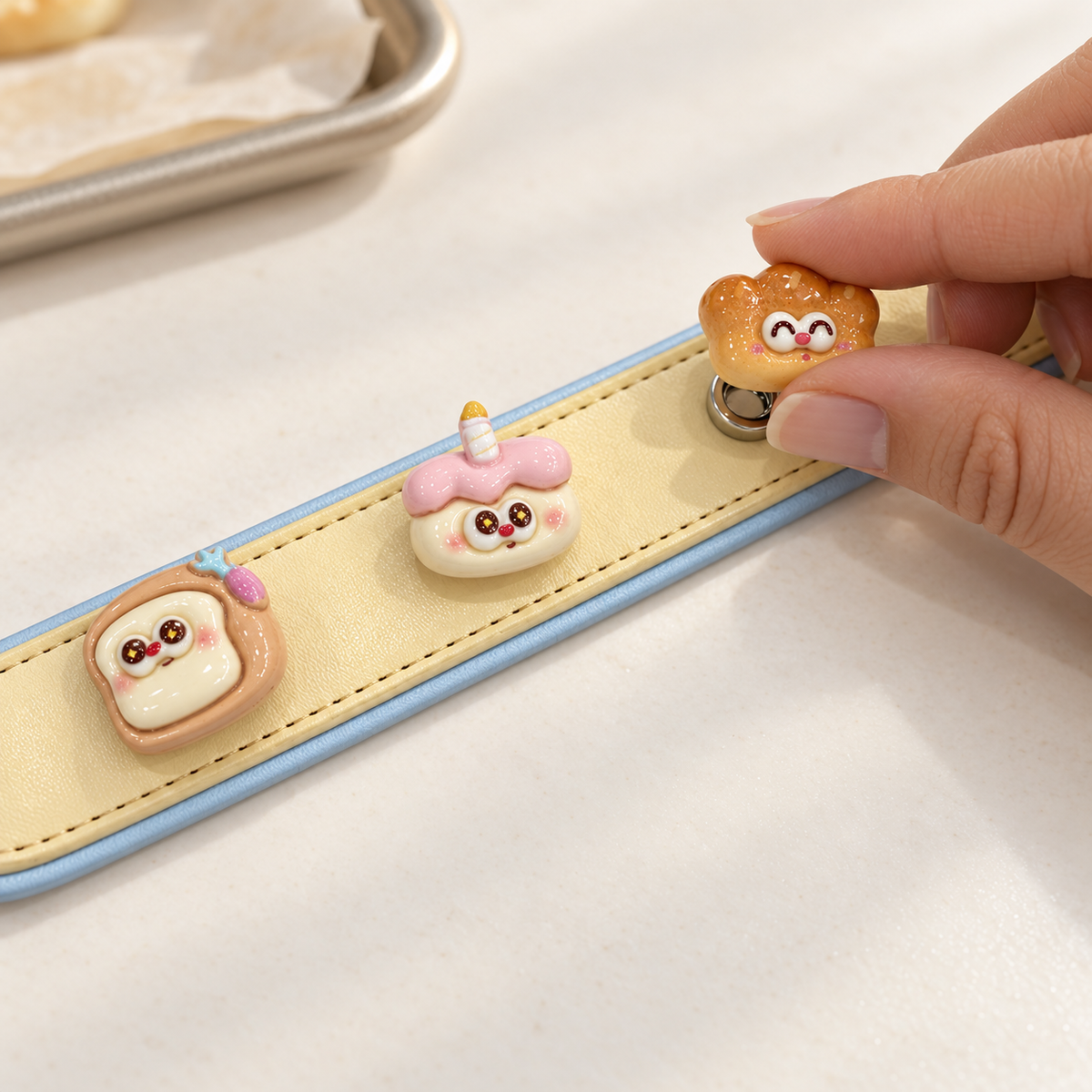 Hand attaching an interchangeable cute bakery dog collar charm to a yellow PETIRIA collar