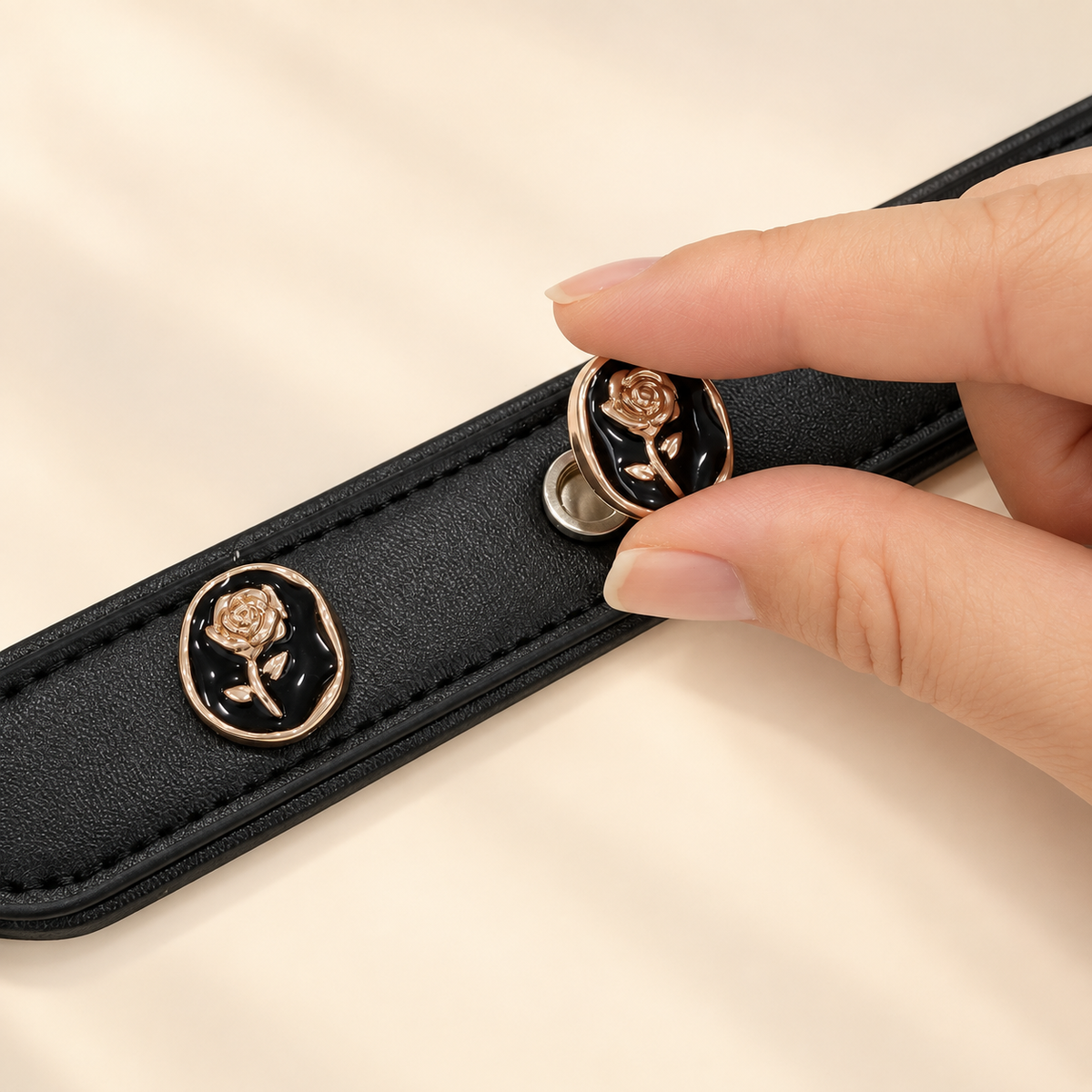 Hand attaching a Black Rose Cameo dog collar charm to a black PETIRIA collar