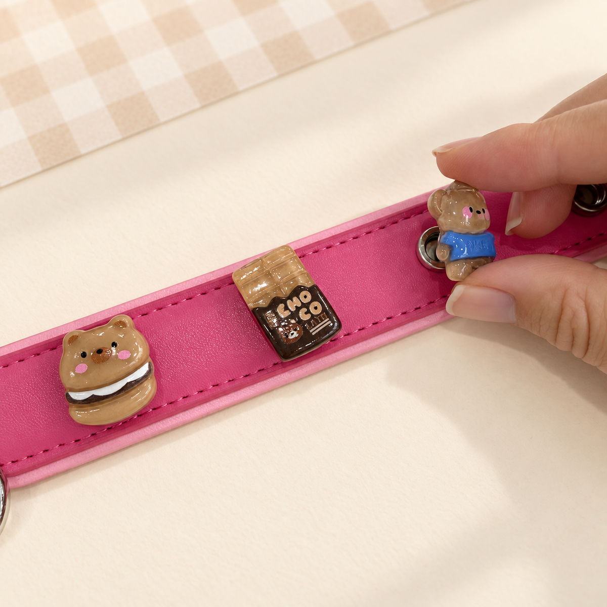 Hand attaching an interchangeable cute character dog collar charm to a pink PETIRIA collar