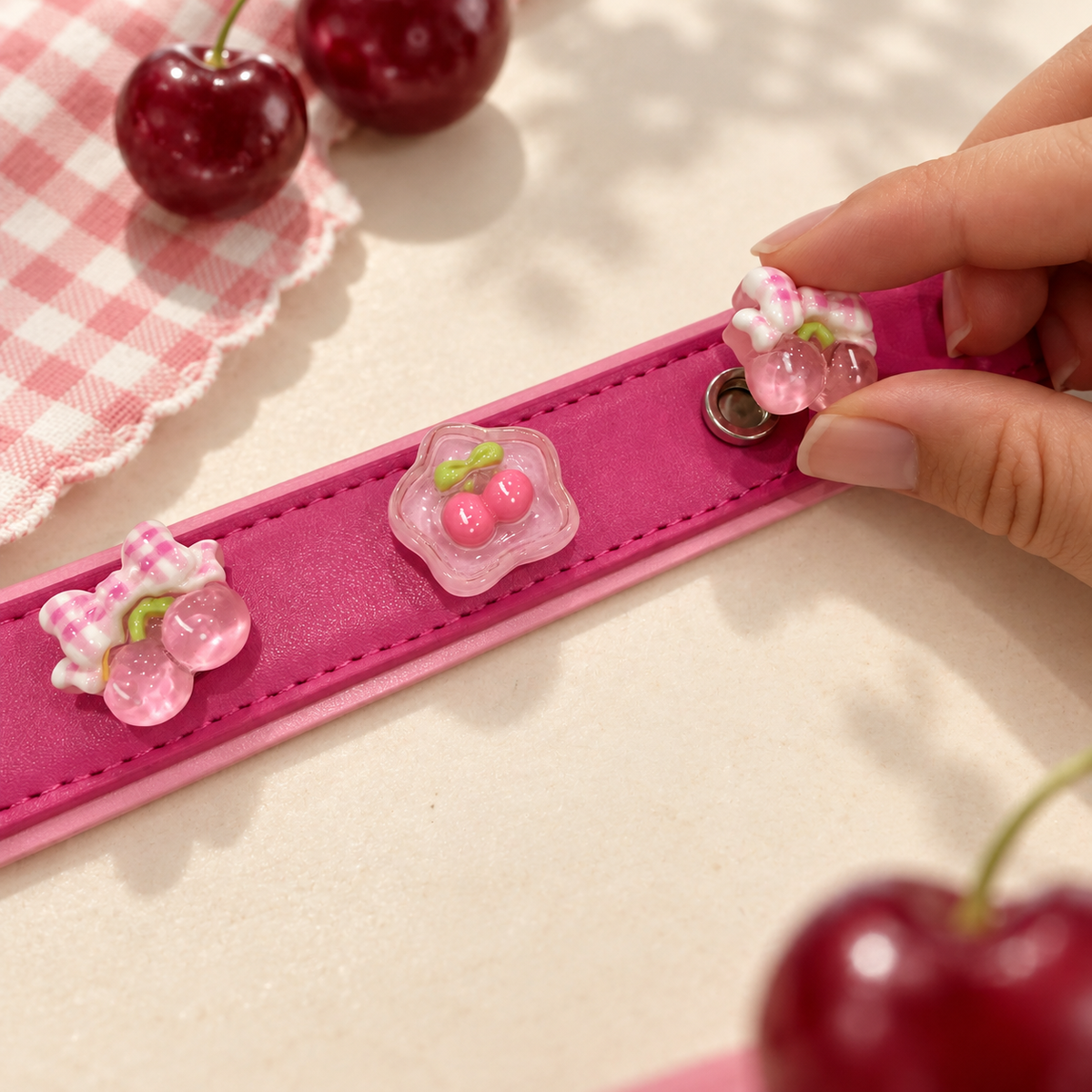 Hand attaching an interchangeable pink cherry dog collar charm to a pink PETIRIA collar