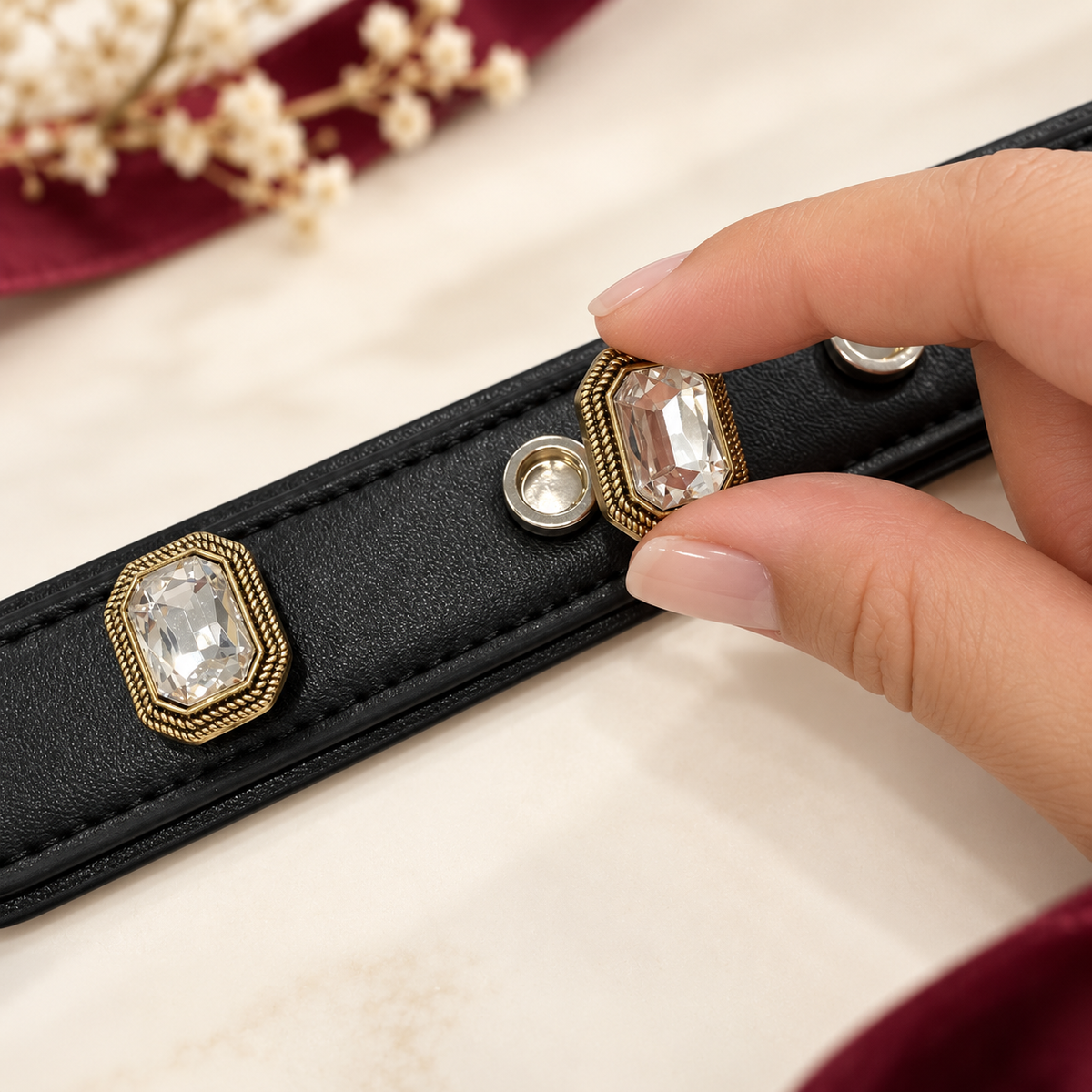 Hand attaching an interchangeable crystal gem charm to a black PETIRIA dog collar