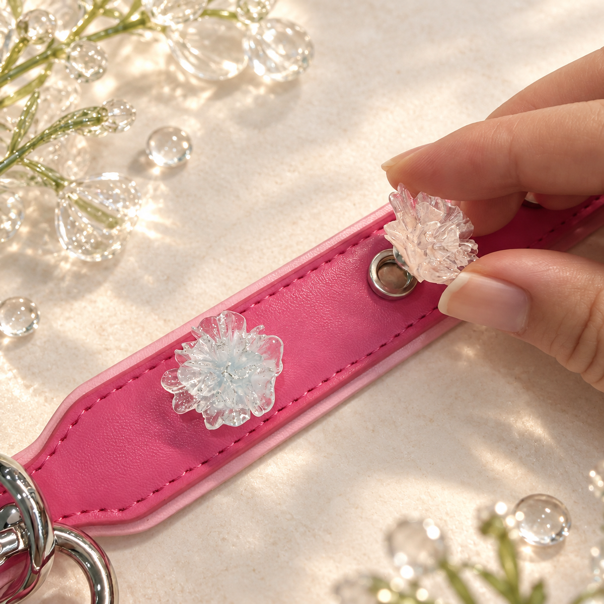 Hand attaching an interchangeable blush pink crystal flower dog collar charm to a pink PETIRIA collar