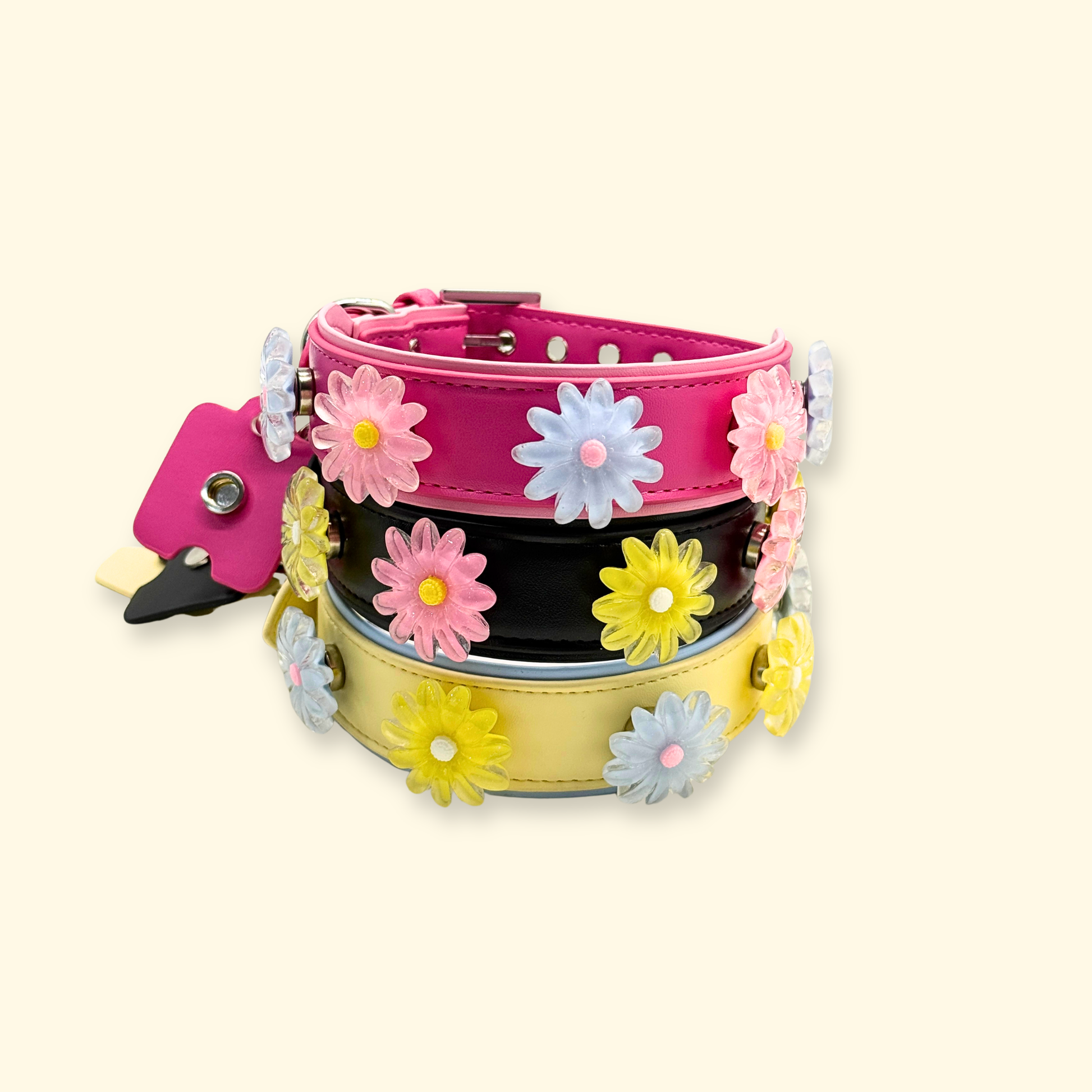 Stacked dog collars in pink, black, and yellow with snap-on daisy flower charms for customizable pet accessories