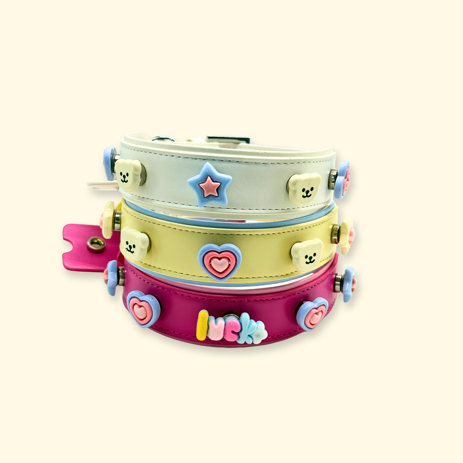 Stacked display of pastel interchangeable dog collars featuring snap-on charms including hearts, stars, and colorful letter designs