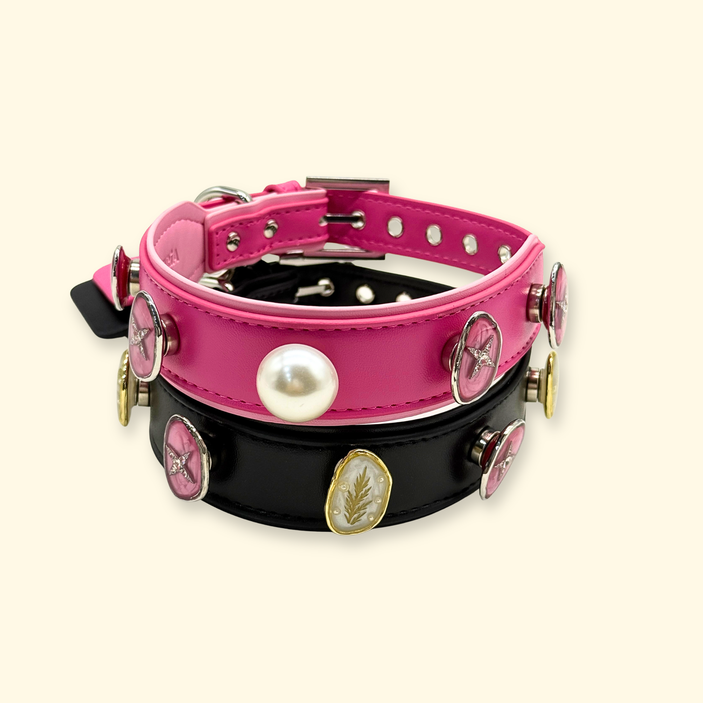 Two interchangeable dog collars in pink and black leather featuring snap-on decorative charms including pearl, star, and leaf designs, styled as a customizable aesthetic pet accessory set for dogs.