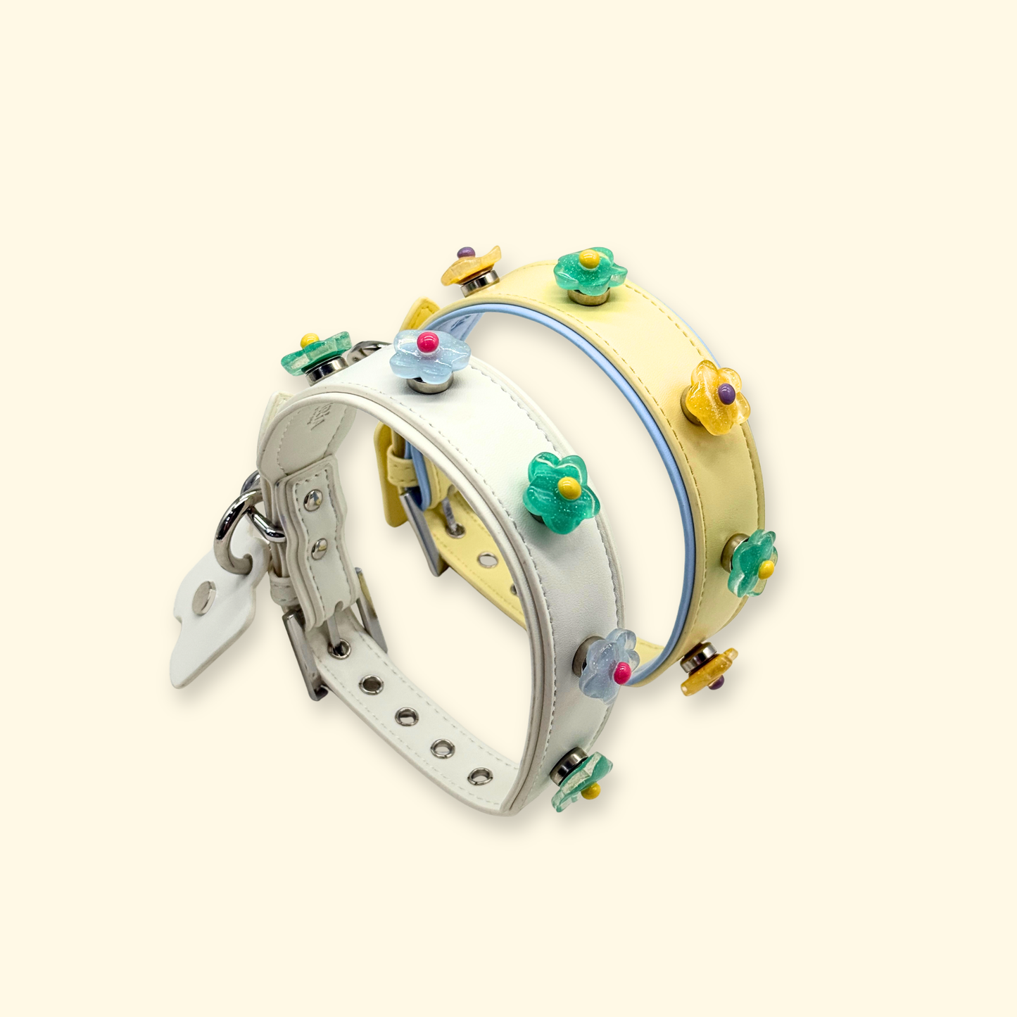 A set of interchangeable dog collars in white, yellow, and blue featuring colorful floral snap-on charms designed for customizable pet styling.