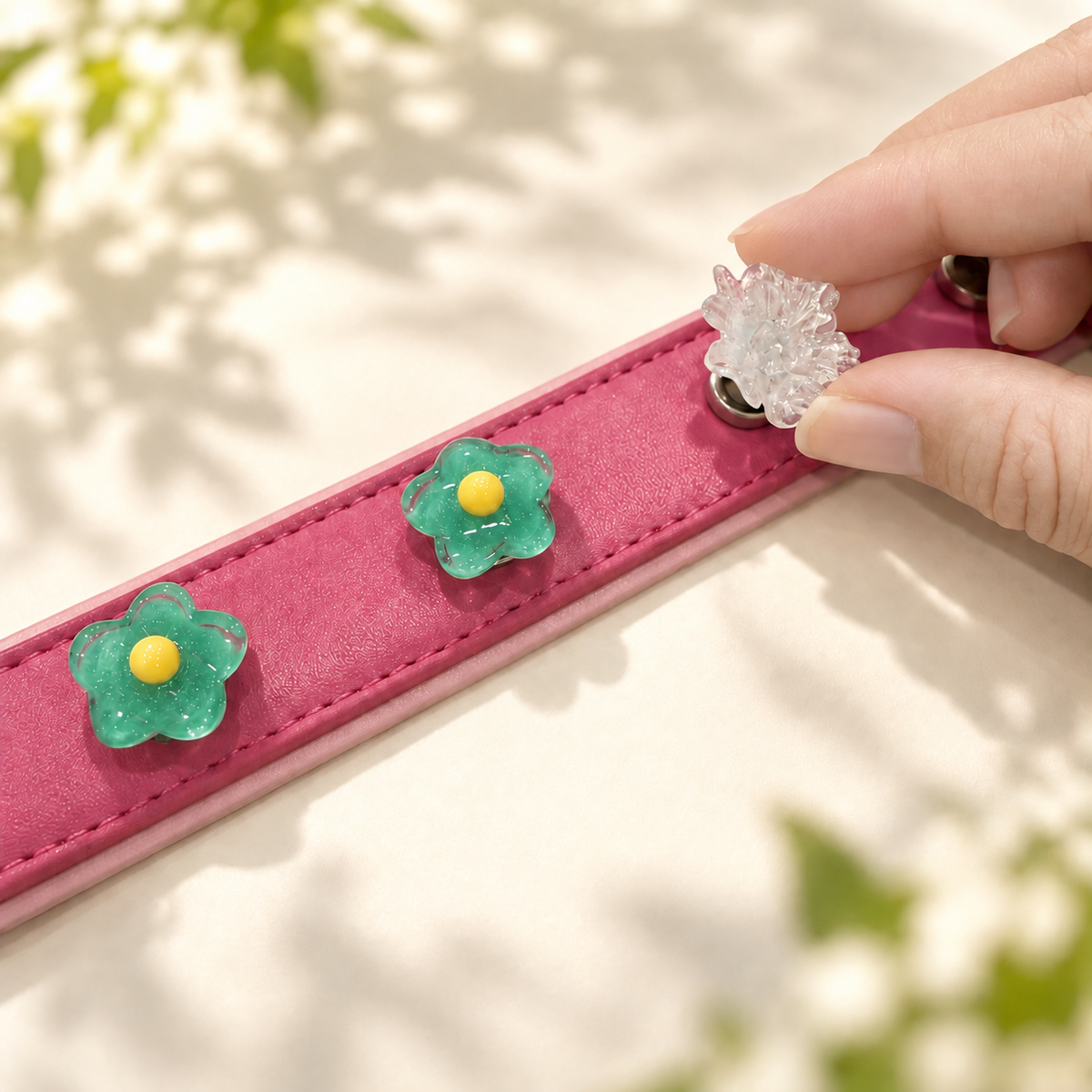 Hand attaching an interchangeable green mini flower dog collar charm to a pink PETIRIA collar