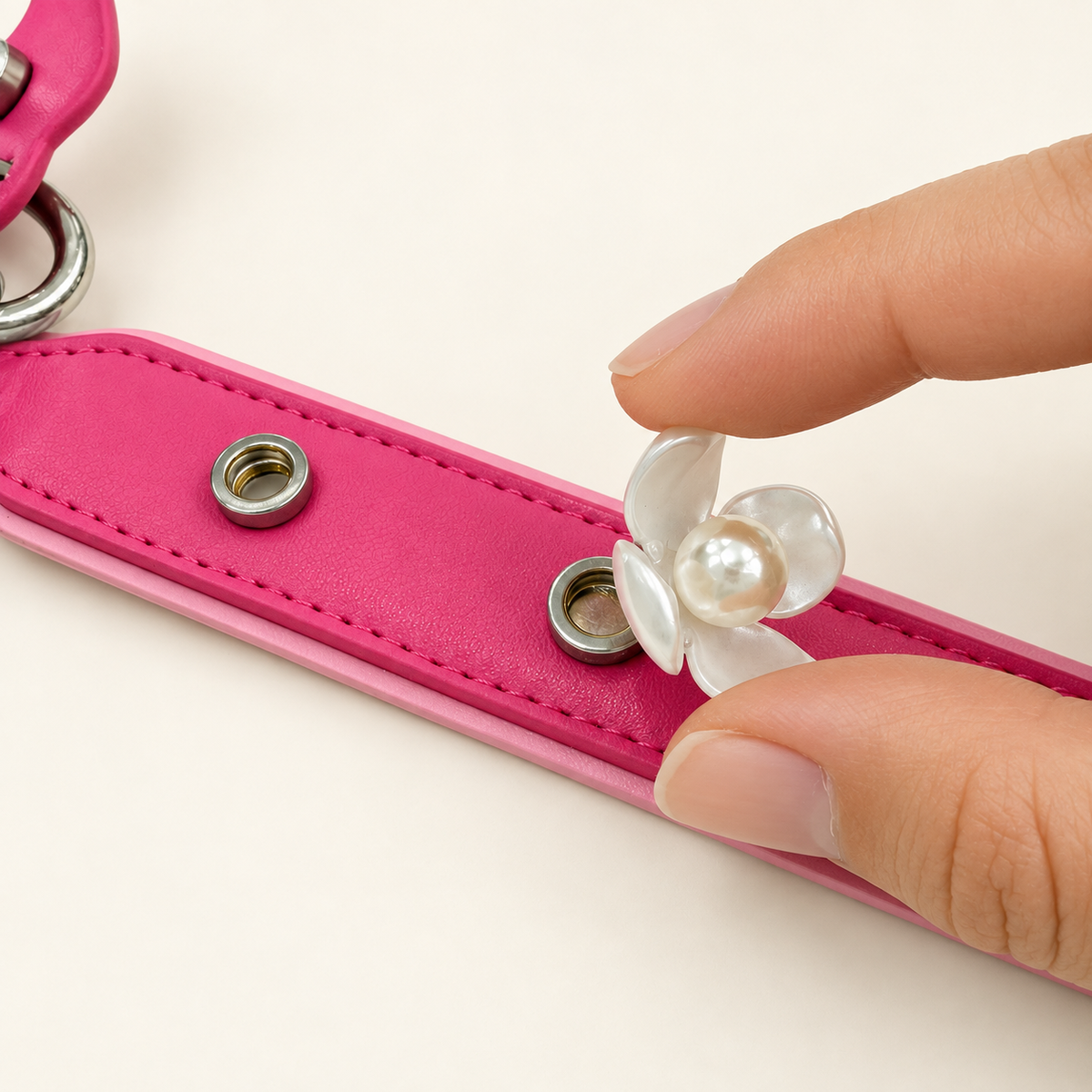 Hand attaching an interchangeable pearl flower dog collar charm to a pink PETIRIA collar