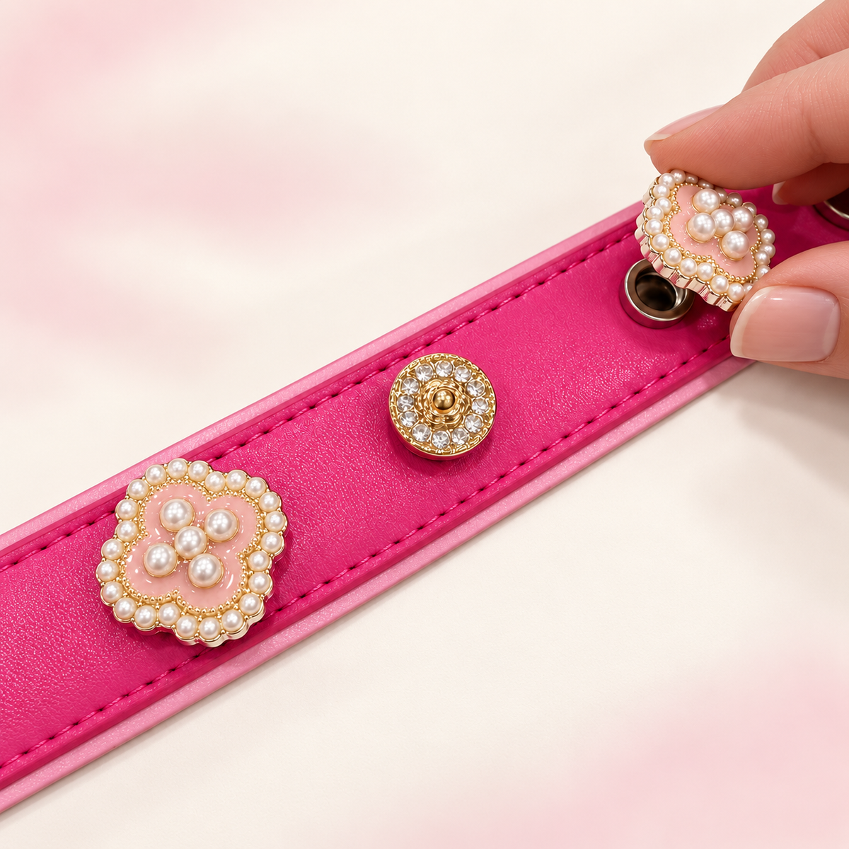 Hand attaching a Pink Pearl Blossom interchangeable dog collar charm to a pink PETIRIA collar