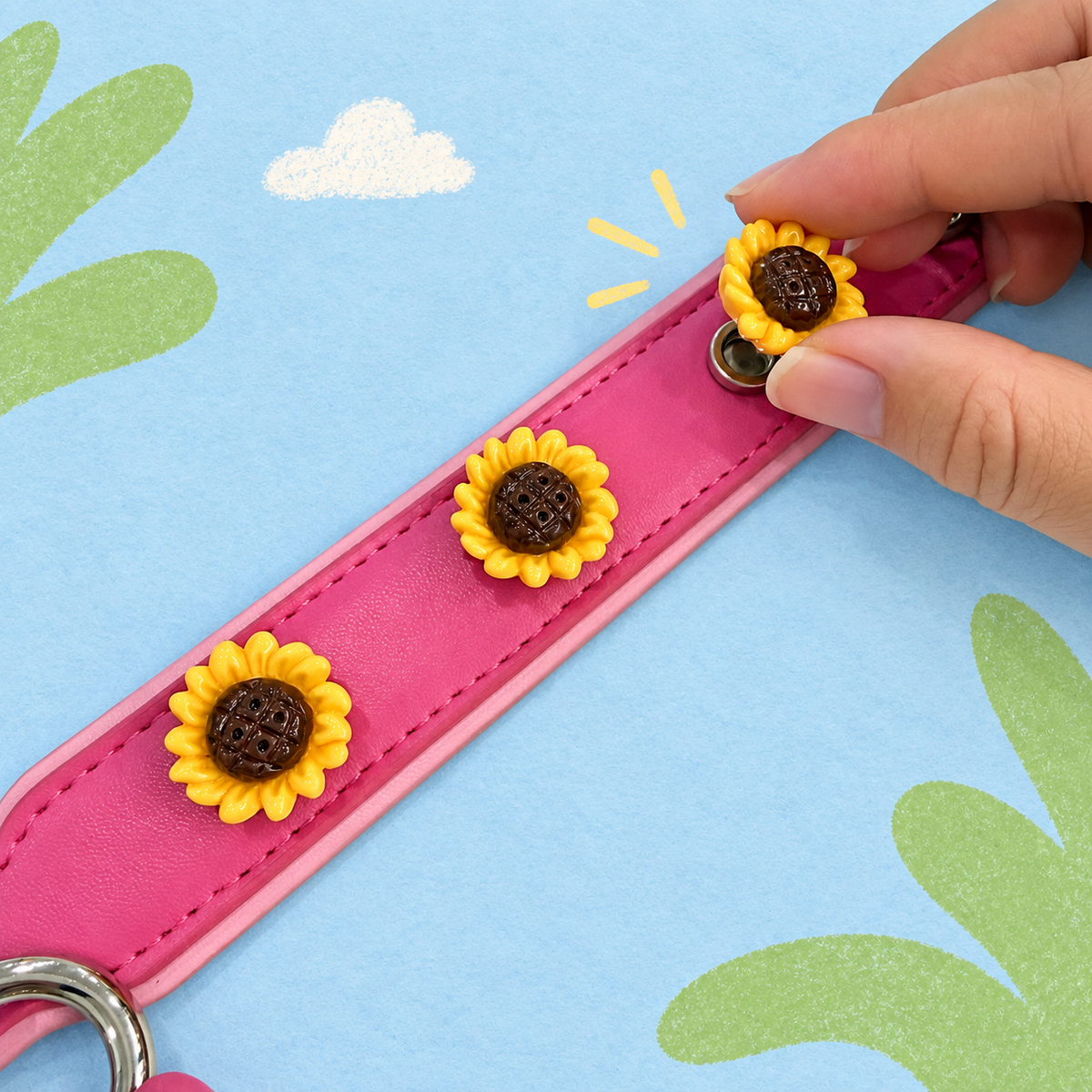 Hand attaching an interchangeable sunflower dog collar charm to a pink PETIRIA collar