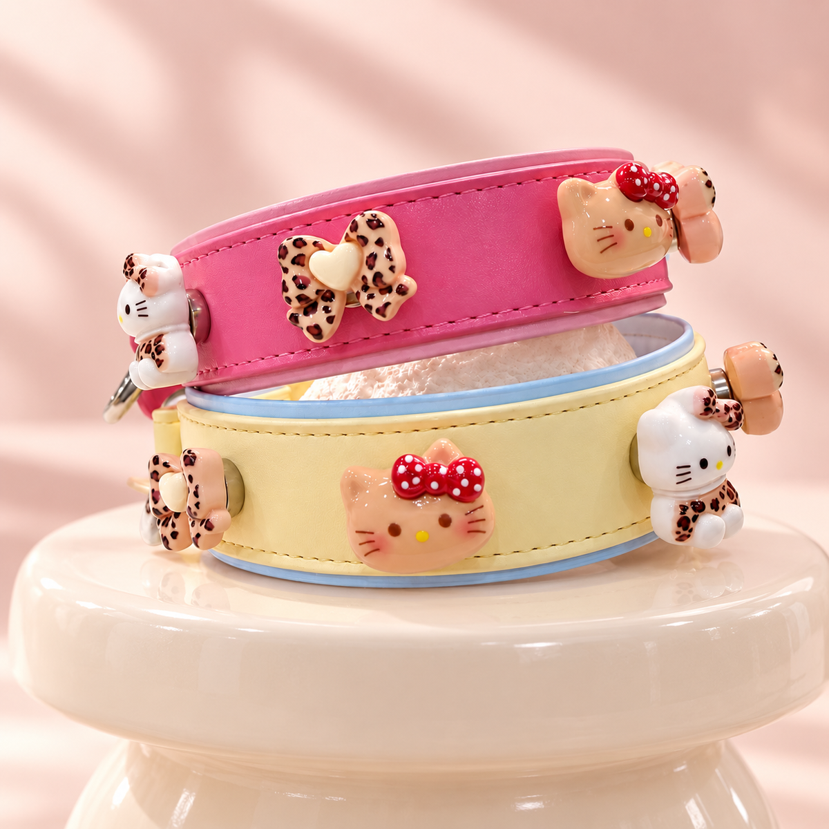 Pink and yellow Petiria dog collars styled with leopard print bow and cat-shaped charms