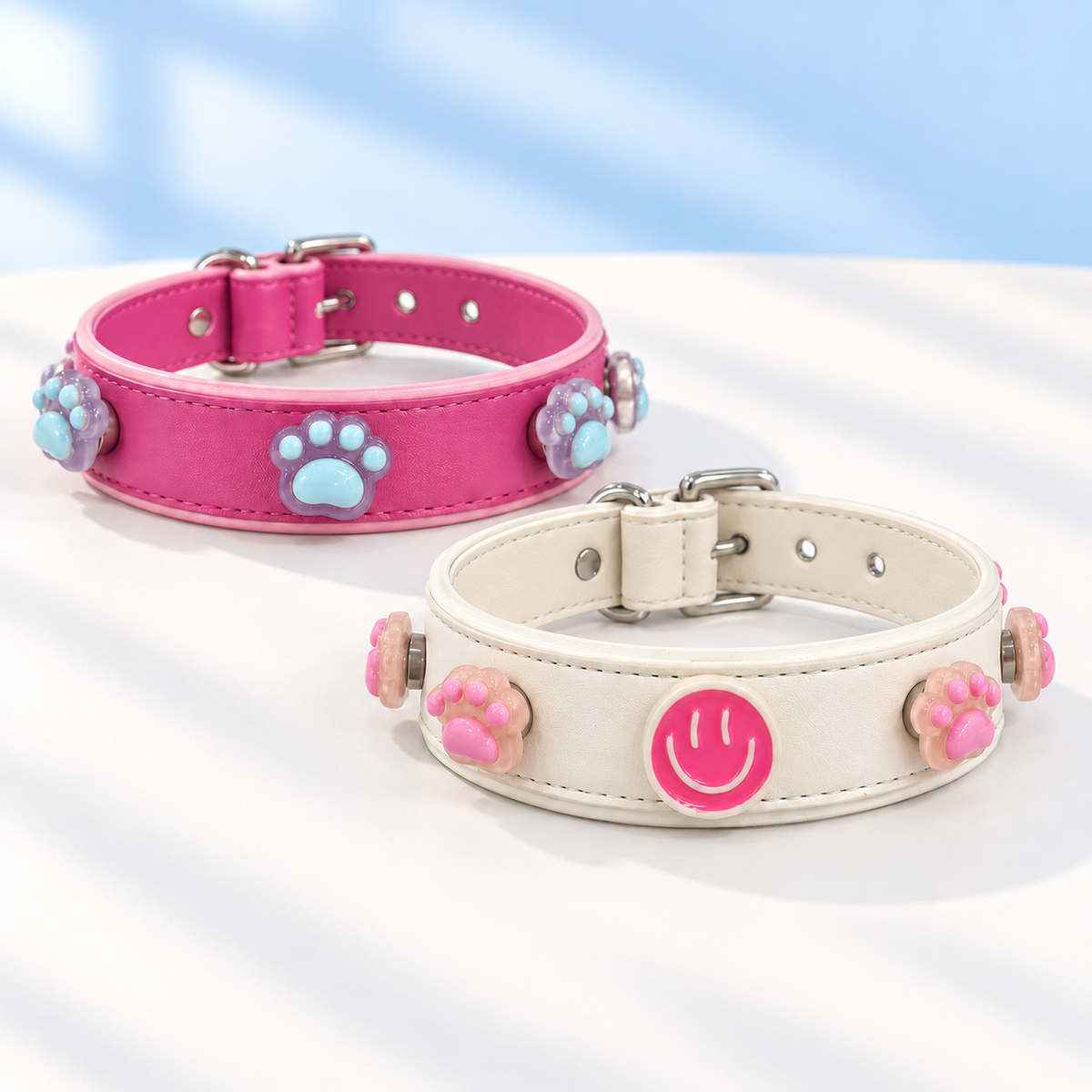 Pink and cream Petiria dog collars styled with colorful paw print and smiley face charms
