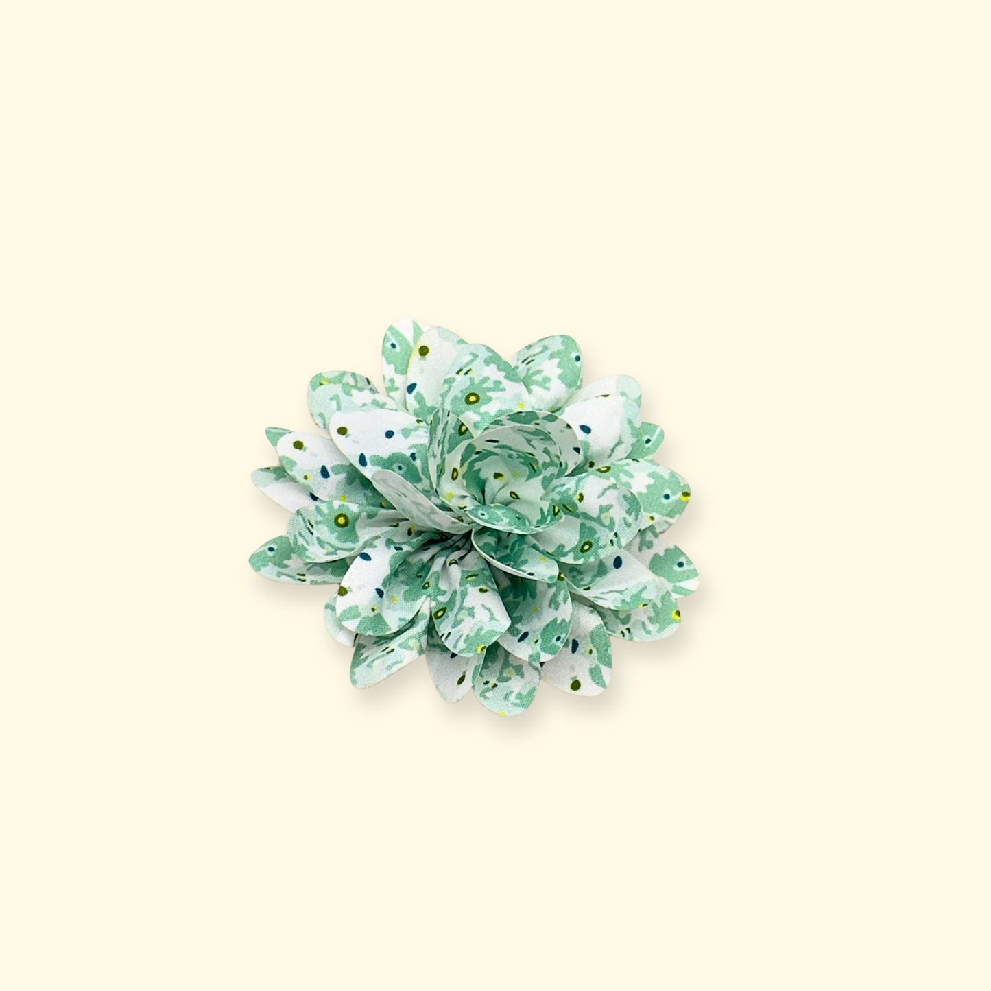 Close-up of Petiria green floral collar charm, highlighting texture and snap-on feature, beige background