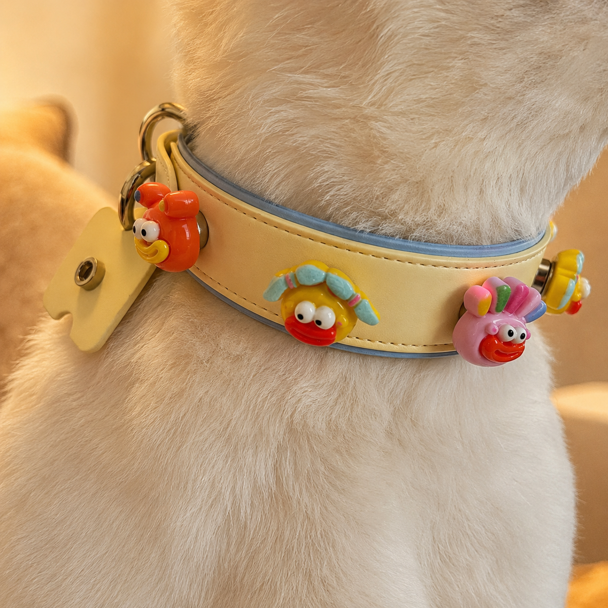 Close up of a light colored dog wearing a yellow emoji charm collar showing playful customizable pet accessory design