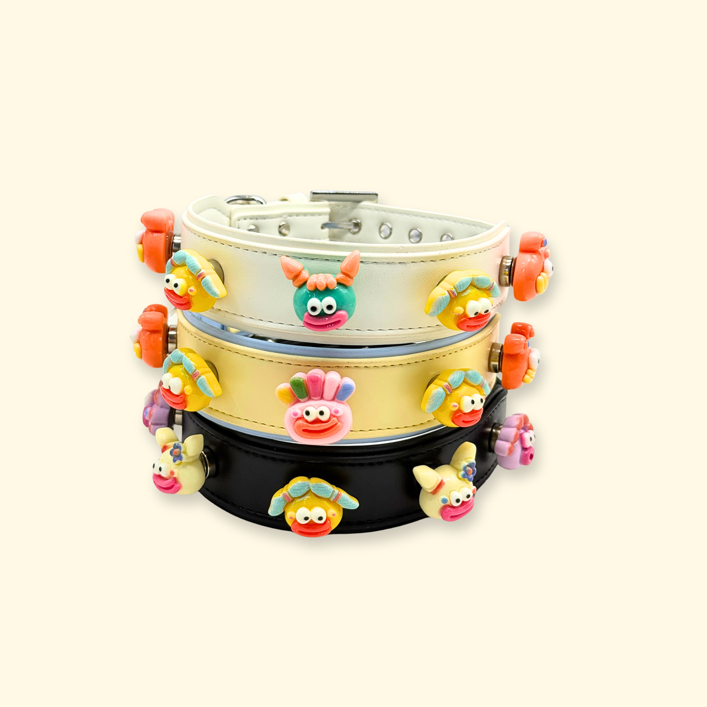 Stacked display of three customizable dog collars in black white and yellow with colorful emoji charms for playful pet styling