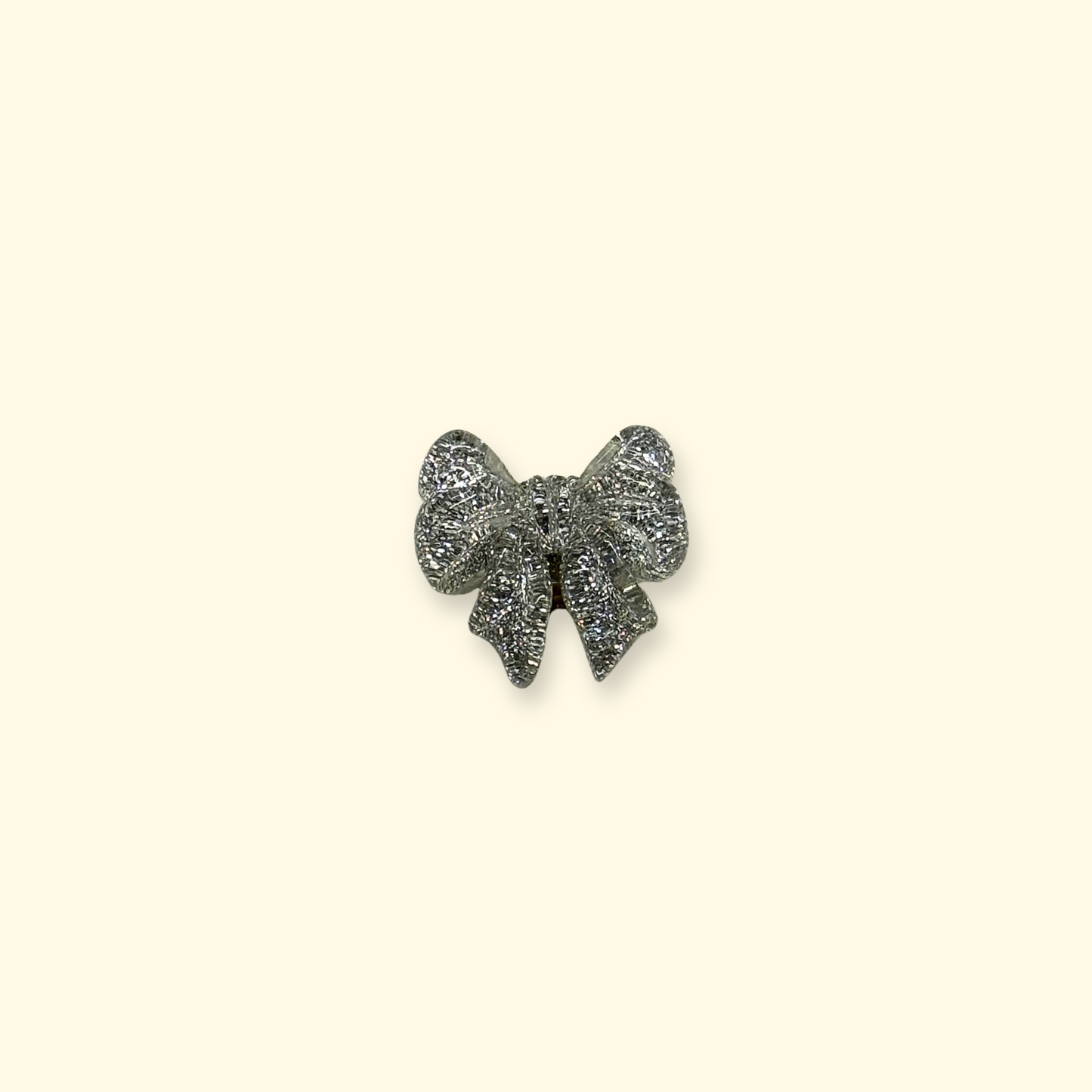 Close-up of Petiria vintage silver bow snap-on dog collar charm with textured metallic finish.