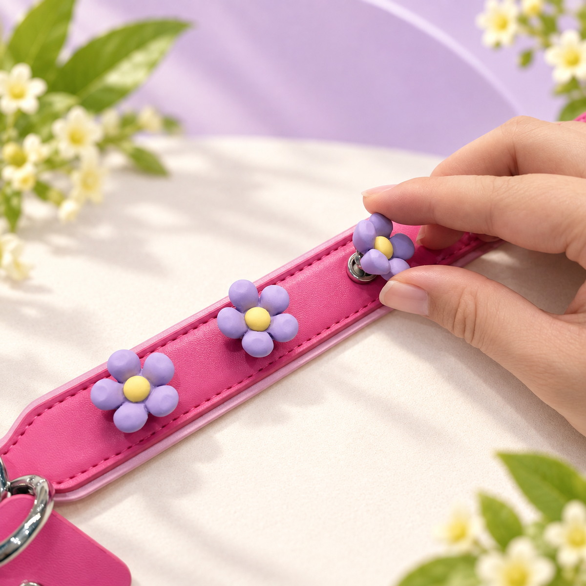 Hand attaching an interchangeable purple daisy dog collar charm to a pink PETIRIA collar